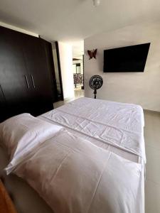 a bedroom with a bed with white sheets and a fan at Acogedor apartamento en San Gil. in San Gil