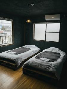 two beds in a room with two windows at まちごとホテルLOOP 小林 in Makata