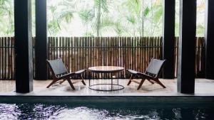a patio with two chairs and a table next to a pool at Escotel Krisnantara in Canggu