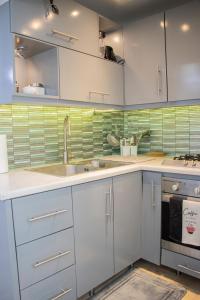 a kitchen with white cabinets and green tiles at EL Bonito II Juan Dolio DR 2 room sleeps6 1queen bed 2twin bed 1sofa bed in Juan Dolio