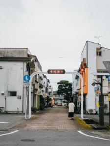 a woman walking down a street under a street sign at まちごとホテルLOOP 小林 in Makata