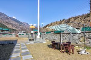 a table and two chairs and an umbrella at Ritu Regency , Himachal Pradesh in Kulu