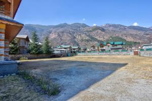 a large yard with houses and mountains in the background at Ritu Regency , Himachal Pradesh in Kulu