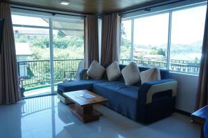 a living room with a blue couch and large windows at Lake infinity Penthouse in Nuwara Eliya