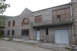 ein Steingebäude mit zwei weißen Türen und einem Balkon in der Unterkunft Eriks guest house in Goris