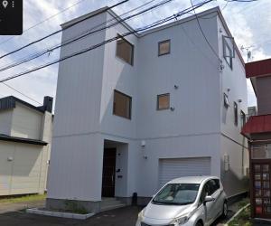 a white house with a car parked in front of it at 〈親子二段ベット室【机＆椅子付き 】〉駐車場無料&地下鉄駅から950m　札幌新築戸 in Sapporo