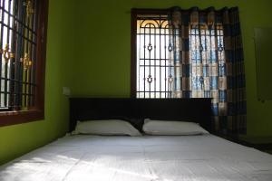 uma cama num quarto verde com uma janela em Pallavi Homestay em Honāvar