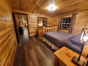 ein Schlafzimmer mit einem Bett in einem Blockhaus in der Unterkunft Luxury Cabin w/ Game Room & Hot Tub at Cave Run Lake in Wellington