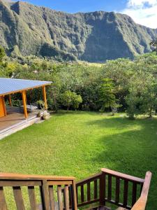 a yard with two benches and a house with mountains at Le cottage in La Plaine des Palmistes