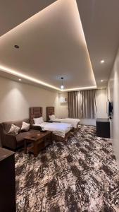 a large room with two beds and a couch at Radiha Hotel Suites in Al Ḩawīyah