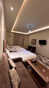 a hotel room with two beds and a couch at Radiha Hotel Suites in Al Ḩawīyah