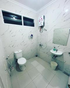 a white bathroom with a toilet and a sink at Villa Omar in Cikujang