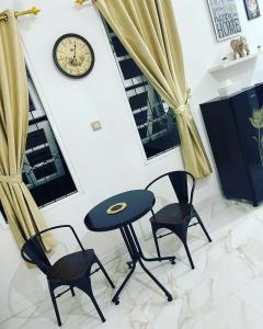a table and two chairs and a clock on a wall at Villa Omar in Cikujang