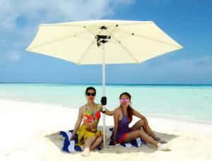 Due donne sedute sotto un ombrellone sulla spiaggia di Adroit Beach Inn a Guraidhoo