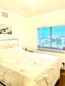 - un lit blanc dans une chambre avec fenêtre dans l'établissement Luxury Beach Condo, à Dania Beach