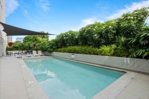 a large swimming pool with chairs and trees at Spaciously Bright 1-Bed Apartment in Brisbane