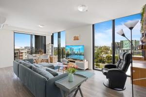 a living room with a couch and chairs and windows at Spaciously Bright 1-Bed Apartment in Brisbane
