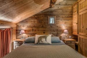 a bedroom with wooden walls and a bed with two lamps at Chalet Colettine - 7 Pièces pour 12 Personnes 09 in Tignes