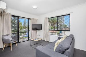 sala de estar con sofá, TV y ventanas en Island Beach Resort, en Gold Coast