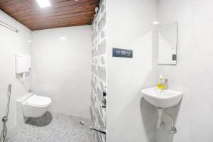 a white bathroom with a toilet and a sink at FabExpress Kirtiraj in Panvel