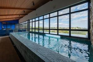 a large swimming pool in a building with windows at Bexp Spaces | Wanderlust Campos do Jordão in Campos do Jordão