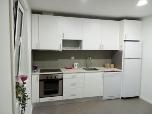 een keuken met witte kasten en een witte koelkast bij Ground Floor Terrace Flat by Porto in São Mamede de Infesta
