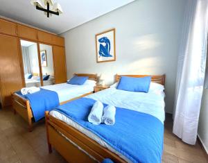 1 Schlafzimmer mit 2 Betten mit blauer Bettwäsche und Handtüchern in der Unterkunft Tranquilo apartamento cerca del Casco Viejo Bilbao in Bilbao