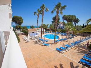 un complexe avec une piscine, des chaises et des palmiers dans l'établissement Hotel Servigroup Romana, à Alcossebre
