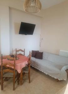 a living room with a couch and a table and a tv at House next to the sea side in Derveni