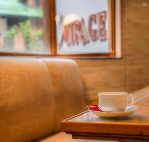 a coffee cup on a table next to a couch at Hotel Mirage in Srinagar