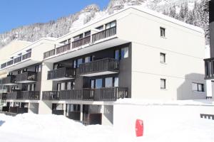 un bâtiment dans la neige avec une montagne en arrière-plan dans l'établissement Résidence Gemeaux - Studio pour 4 Personnes 06, à Flaine