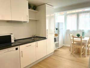 biała kuchnia ze zlewem i stołem w obiekcie La Casa de Niku w mieście Bilbao