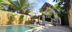 a house with a swimming pool and an umbrella at 3 Angels One-Bedroom Villa in Gili Islands