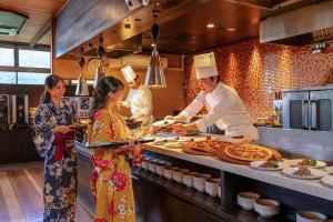 a group of people standing in a kitchen preparing food at Ooedo Onsen Monogatari Premium Kinosaki in Toyooka