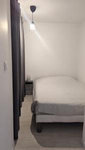 biała sypialnia z łóżkiem i lampką w obiekcie Studio avec coin nuit 150m de la plage w mieście Le Lavandou