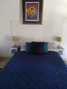 a blue bed in a bedroom with two lamps at Eden Guest Farm in Bloemfontein