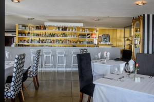 a restaurant with white tables and chairs and a bar at Francolin Lodge in Nelspruit