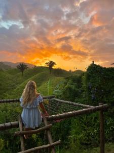 Una bambina in piedi su una recinzione che guarda il tramonto di The Valley Tayrona hostel- A social jungle hostel a El Zaino