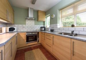 a kitchen with wooden cabinets and a sink at Dolwar in Abersoch