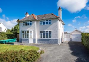 a white house with a boat in the driveway at Dolwar in Abersoch