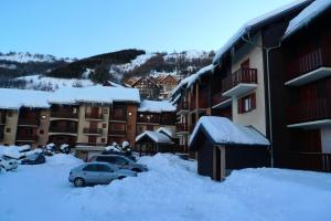 um parque de estacionamento coberto de neve ao lado de edifícios em Résidence La Croix Du Sud - Studio pour 4 Personnes 14 em Valloire