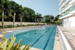 a person swimming in a swimming pool next to a building at Suíte & Flat Premium Rio Stay - Rio Centro in Rio de Janeiro