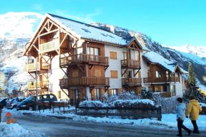 two people walking in front of a house in the snow at Chalet Du Regain - 3 Pièces pour 8 Personnes 94 in Valloire