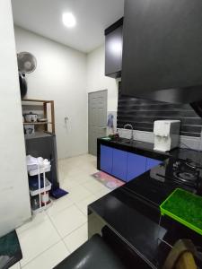a kitchen with a black counter top and a stove at Doleena's Homestay in Sitiawan