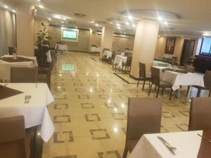 una sala da pranzo con tavoli e sedie bianchi e un piano di Holiday Hotel Addis Ababa ad Addis Abeba