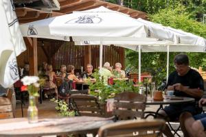 a group of people sitting at tables under an umbrella at Guesthouse Draga in Begunje na Gorenjskem