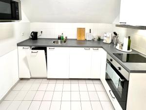 a kitchen with white cabinets and a sink at Modernes Apartment mit Blick zur Elbe in Klipphausen +5 photos