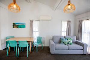 sala de estar con sofá, mesa y sillas en Tāhuna Beach Holiday Park, en Nelson