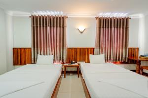 um quarto com duas camas e um relógio na parede em Holiday Hotel em Kampong Speu