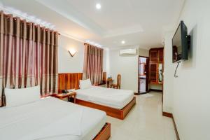 Habitación de hotel con 2 camas y TV de pantalla plana. en Holiday Hotel en Kampong Speu